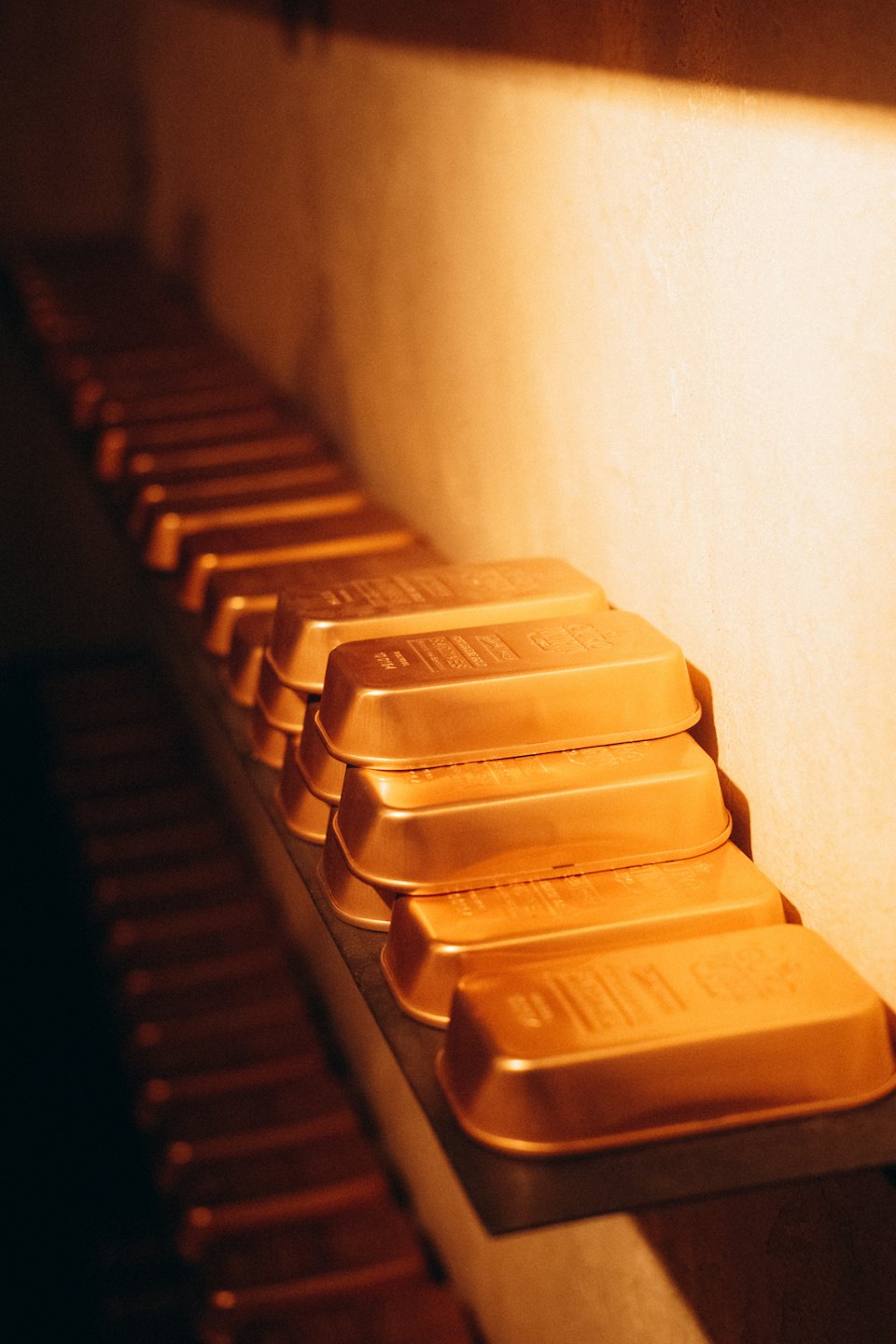 Reihen von Goldbarren, die ordentlich auf einem Metallregal gestapelt sind.