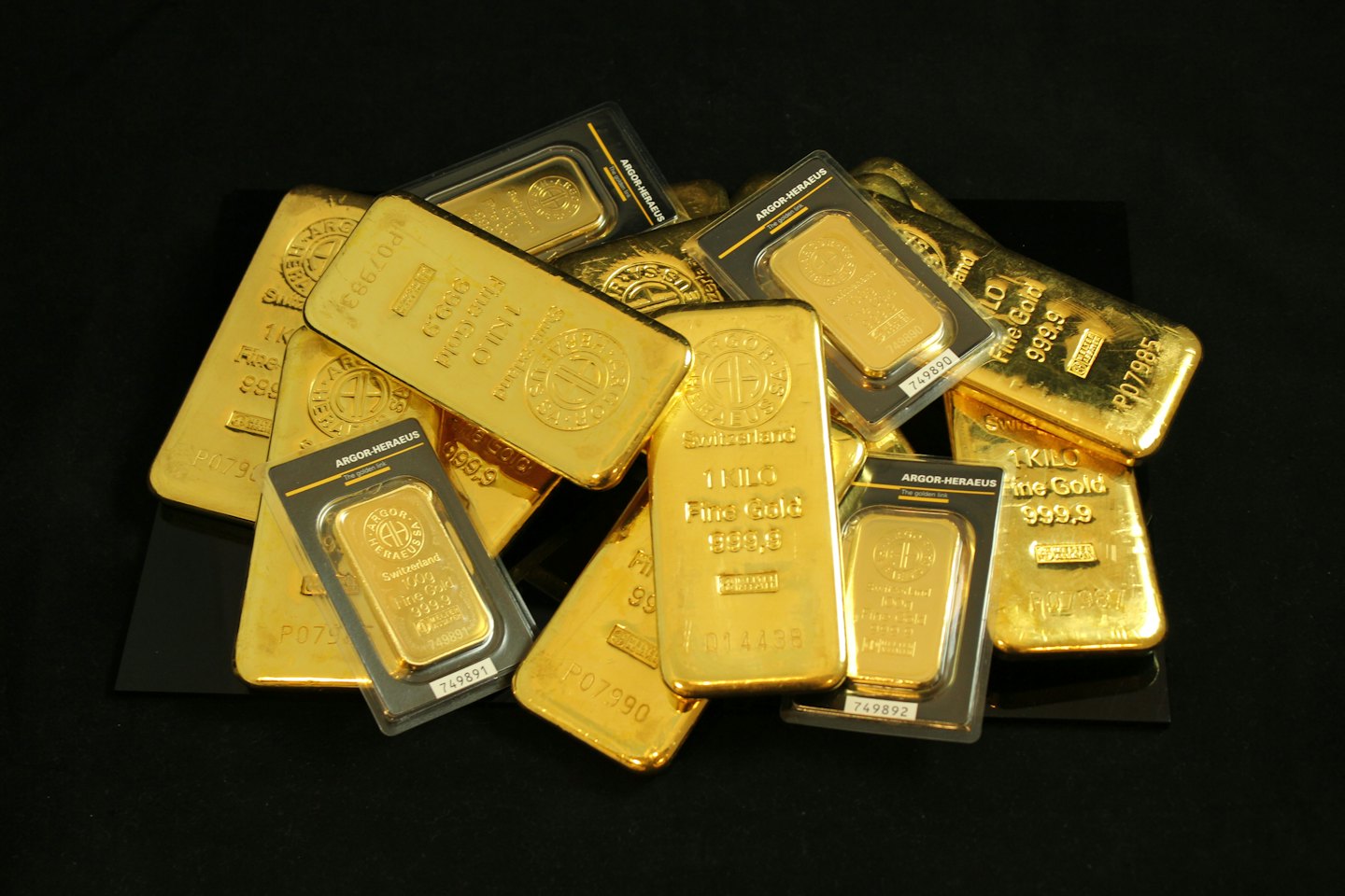 Goldbarren und Barren auf schwarzem Hintergrund gestapelt.